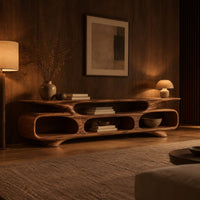 Low tv stand with three open oval cubbies under a sculpted slab top in an evening living room with walnut wall paneling