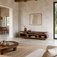 Low tv stand with three open oval cubbies under a sculpted slab top in a bright open plan living room
