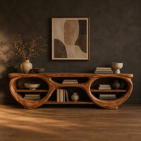 Tv stand with two large oval openings, open shelves and carved organic edges in a dark studio against a charcoal plaster wall