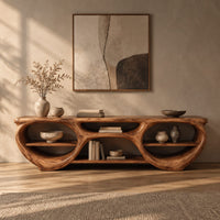 Corner detail of tv stand with two large oval openings, open shelves and carved organic edges beside wood, brass and linen samples