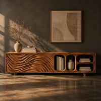 Corner detail of low tv stand with wave carved fronts and open pill shaped cubbies beside wood, brass and linen samples