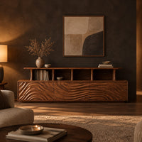 Tv stand with wave carved front panels and a raised open display shelf in a dark living room at golden hour