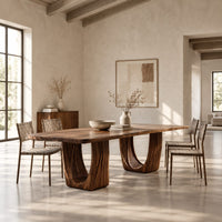 Rectangular dining table with a slab top and twin fluted arch pedestals in a bright open plan dining room