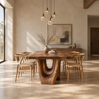 Dining table with a natural edge slab top and two sculpted arch legs in a bright open plan dining room