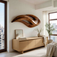 Twin crescent carved wood wall sculpture above a light oak sideboard in daylight