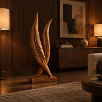 Twin feather sculpture with carved veins crossing over a solid wood plinth in an evening living room with walnut wall paneling