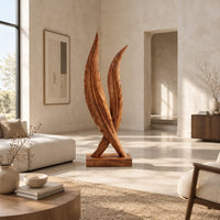 Twin feather sculpture with carved veins crossing over a solid wood plinth in a bright open plan living room