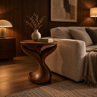 Pedestal side table with a round top, twin fins and a curled foot in an evening living room with walnut wall paneling
