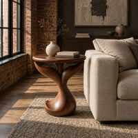 Pedestal side table with a round top, twin fins and a curled foot in an industrial loft living room with exposed brick