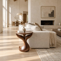 Pedestal side table with a round top, twin fins and a curled foot in a bright open plan living room