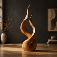 Twin flame wood sculpture with two tall tips and a smooth teardrop base in a dark studio against a charcoal plaster wall