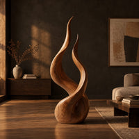 Twin flame wood sculpture with two tall tips and a smooth teardrop base in a dark living room at golden hour