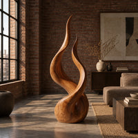Twin flame wood sculpture with two tall tips and a smooth teardrop base in an industrial loft living room with exposed brick