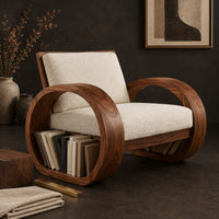 Corner detail of accent chair with two large hoop shaped side frames and cream cushions beside wood, brass and linen samples