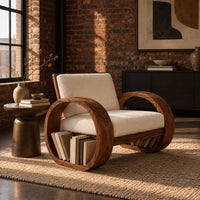 Accent chair with two large hoop shaped side frames and cream cushions in an industrial loft living room with exposed brick
