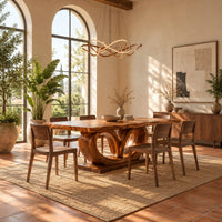 Rectangular dining table on a base of two large open loops in a bright dining room with arched windows and plants