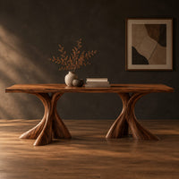 Rectangular dining table on two flared twisting pedestal bases in a dark studio against a charcoal plaster wall