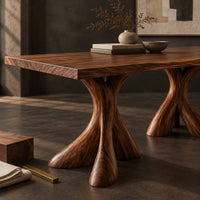 Corner detail of rectangular dining table on two flared twisting pedestal bases beside wood, brass and linen samples