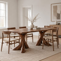 Rectangular dining table on two flared twisting pedestal bases in a Scandinavian dining room with white walls