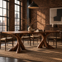Rectangular dining table on two flared twisting pedestal bases in an industrial loft dining room with exposed brick