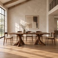 Rectangular dining table on two flared twisting pedestal bases in a bright open plan dining room