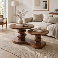 Coffee table with two round tops on carved stems and one shared base in a Scandinavian living room with white walls