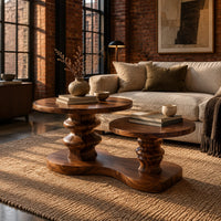 Coffee table with two round tops on carved stems and one shared base in an industrial loft living room with exposed brick