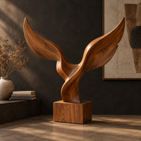 Twin wing sculpture with swept tips rising from a square wooden block, three-quarter view showing the grain