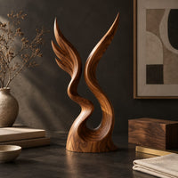 Corner detail of twin wing sculpture rising from one swirled base to two sharp tips beside wood, brass and linen samples