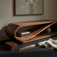 Corner detail of twist loop TV console with a diagonal inner sweep beside wood, brass and linen samples