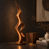 Corner detail of tall floor lamp with a pointed tip, open twisting body and glowing edges beside wood, brass and linen samples