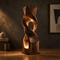 Twisted wooden block floor lamp with an oval window and glowing base opening in a dark studio against a charcoal plaster wall