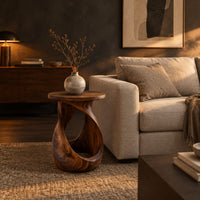 Twisted side table with a circular top and open loop base in a dark living room at golden hour
