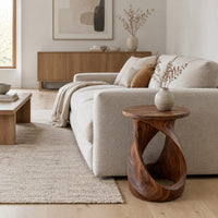 Twisted side table with a circular top and open loop base in a Scandinavian living room with white walls