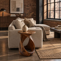 Twisted side table with a circular top and open loop base in an industrial loft living room with exposed brick