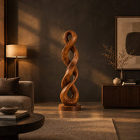 Twisted wood sculpture of two intertwined loops with a flat disc foot in a dark living room at golden hour