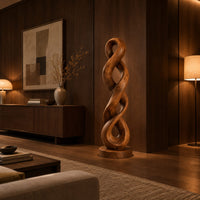 Twisted wood sculpture of two intertwined loops with a flat disc foot in an evening living room with walnut wall paneling