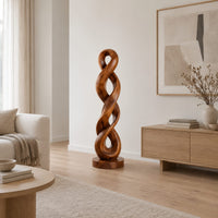 Twisted wood sculpture of two intertwined loops with a flat disc foot in a Scandinavian living room with white walls