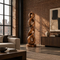 Twisted wood sculpture of two intertwined loops with a flat disc foot in an industrial loft living room with exposed brick