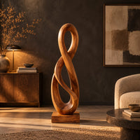 Twisted figure eight wood sculpture with two open loops on a block base in a dark living room at golden hour