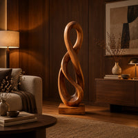 Twisted figure eight wood sculpture with two open loops on a block base in an evening living room with walnut wall paneling