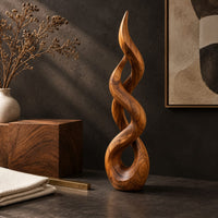 Corner detail of twisted flame shaped sculpture with open loops rising to a pointed tip beside wood, brass and linen samples