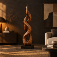Twisted flame shaped sculpture with open loops rising to a pointed tip in a dark living room at golden hour