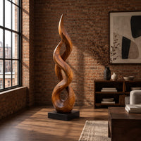 Twisted flame shaped sculpture with open loops rising to a pointed tip in an industrial loft living room with exposed brick