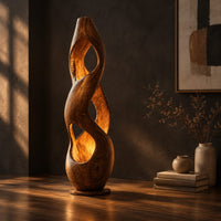 Tall twisted wooden floor lamp with open cutouts that glow warm amber, three-quarter view showing the grain