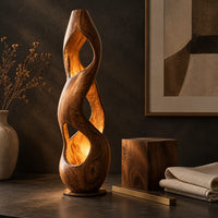 Corner detail of tall twisted wooden floor lamp with open cutouts that glow warm amber beside wood, brass and linen samples