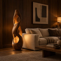 Tall twisted wooden floor lamp with open cutouts that glow warm amber in an evening living room with walnut wall paneling