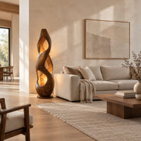 Tall twisted wooden floor lamp with open cutouts that glow warm amber in a bright open plan living room
