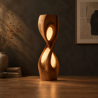 Tall twisted floor lamp with two teardrop openings that glow in a dark studio against a charcoal plaster wall