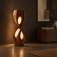 Tall twisted floor lamp with two teardrop openings that glow, three-quarter view showing the grain